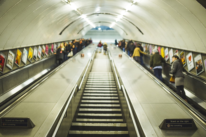 Long escalator in a busy underground metro station tunnel