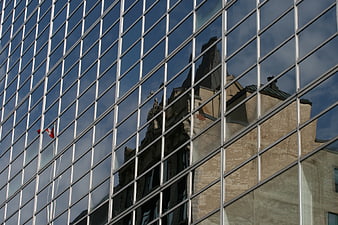 Reflection of historic building and Canadian flag in modern glass facade