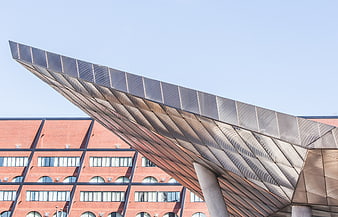 Modern steel overhang architecture against red brick building