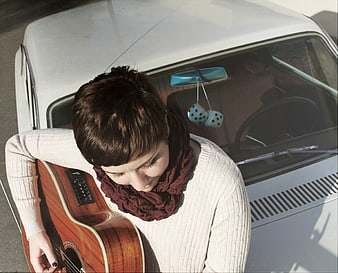 High angle view of woman with guitar leaning on vintage car