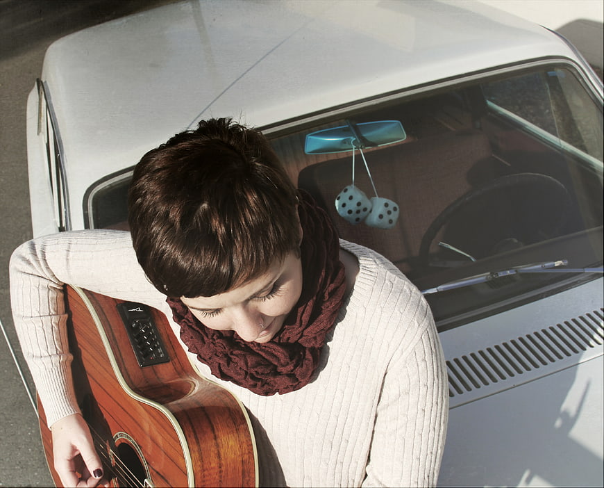 High angle view of woman with guitar leaning on vintage car