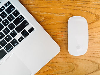 Top view of silver laptop and white mouse on wooden desk