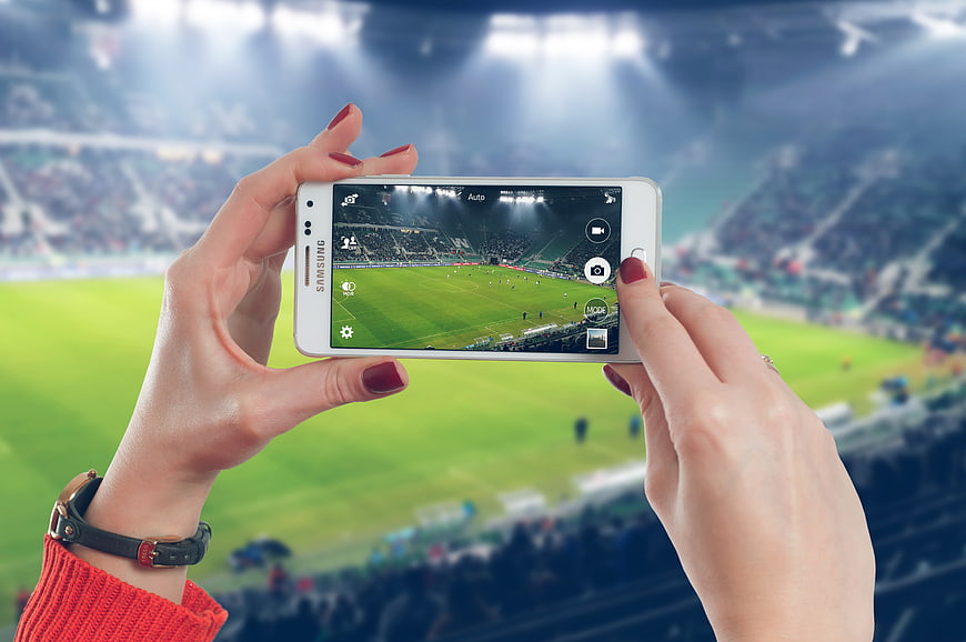 Woman taking photo of soccer stadium with smartphone