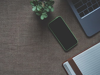 Flat lay workspace with green smartphone, laptop, and notebook