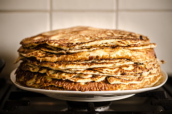 Stack of golden homemade pancakes on white plate