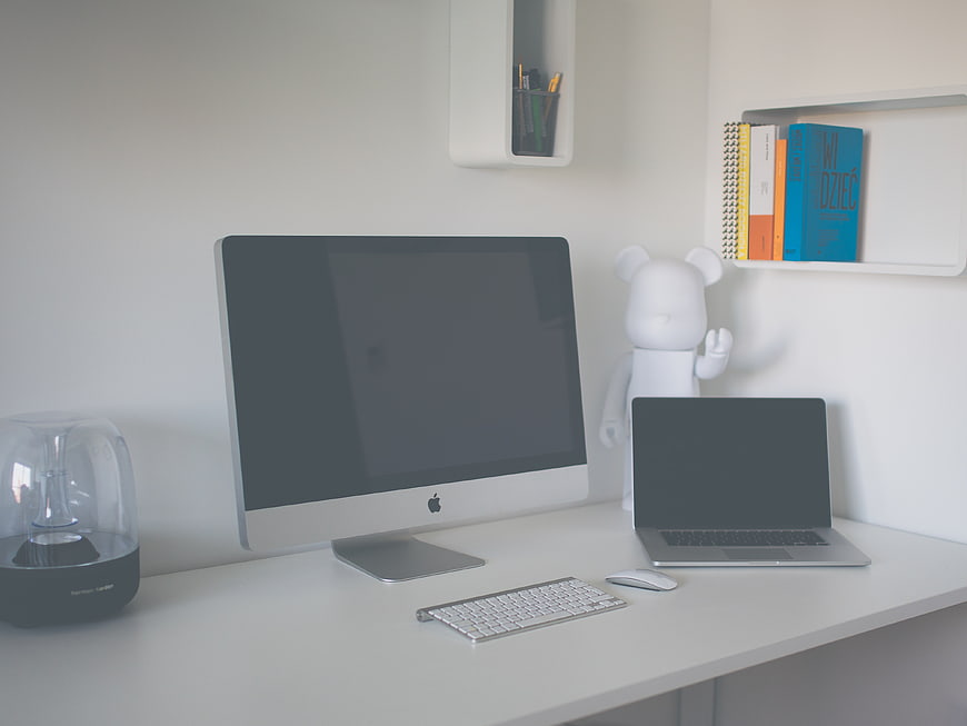 Minimalist white home office desk with iMac and laptop