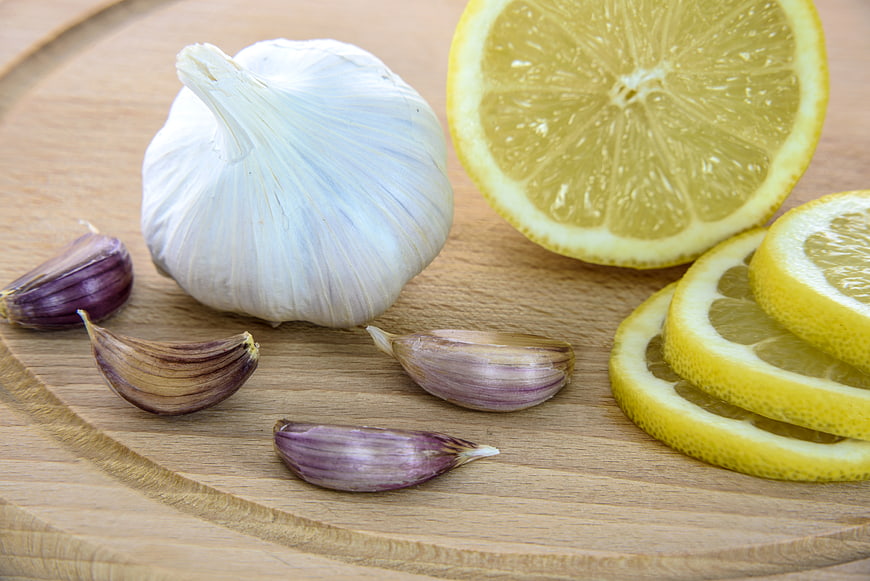 Fresh garlic bulb and lemon slices on wooden board