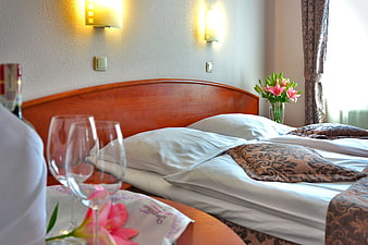 Romantic hotel room with wine, glasses, and flowers on bed