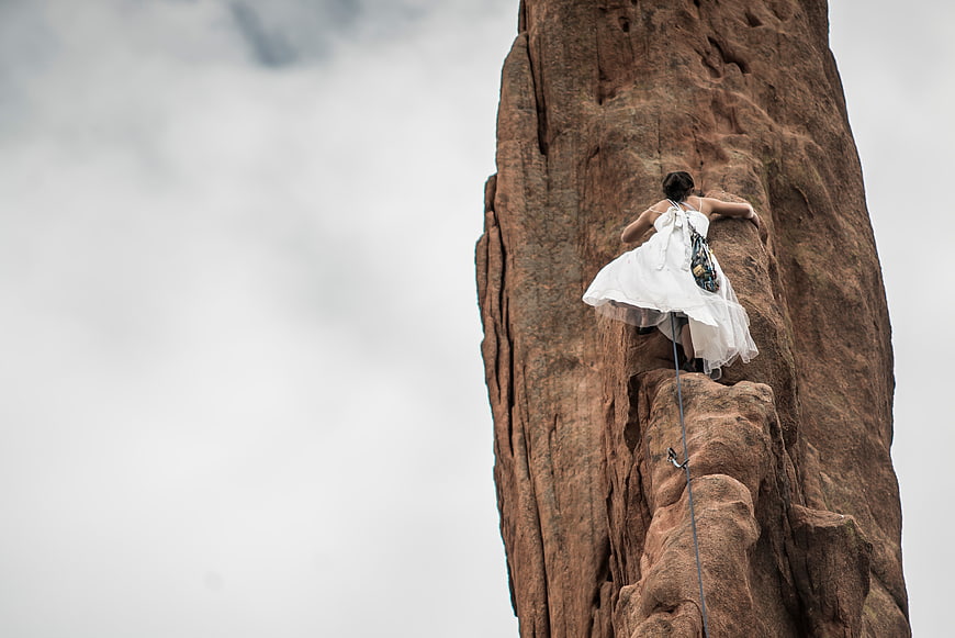 Woman in white dress rock climbing on red sandstone