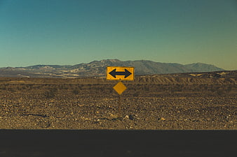 Yellow road sign in desert landscape with mountains