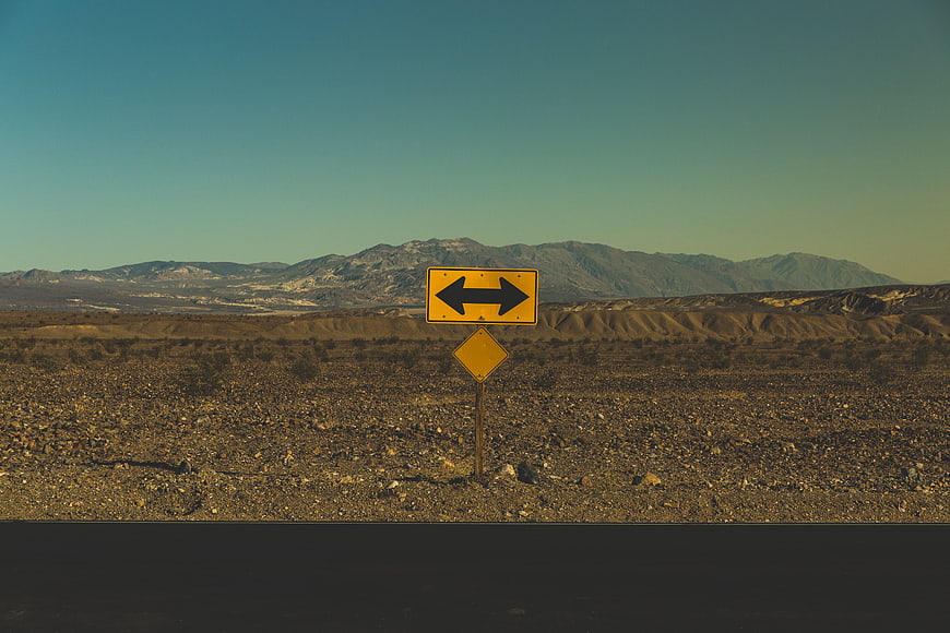 Yellow road sign in desert landscape with mountains