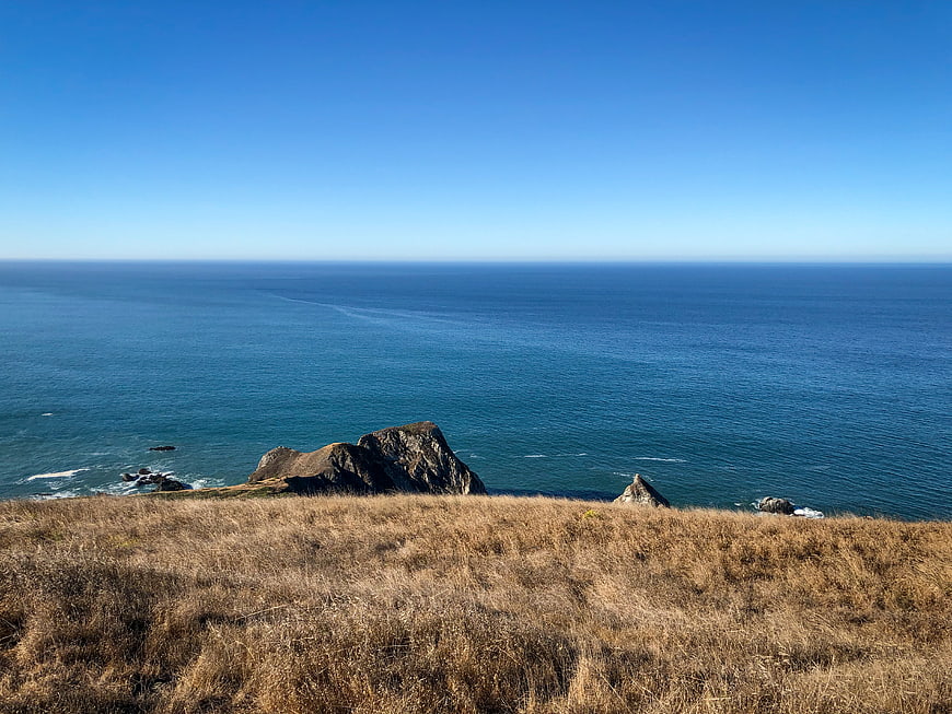 Scenic coastal landscape with dry grass and blue ocean horizon