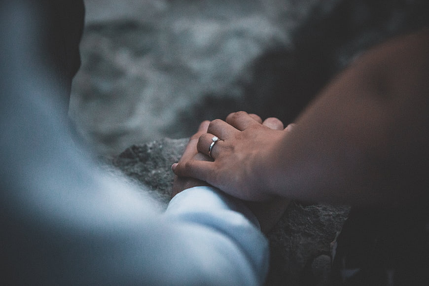 Close-up of couple holding hands with engagement ring