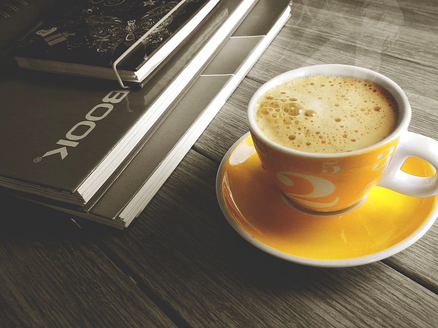 Steaming Coffee Cup and Books on Wooden Table