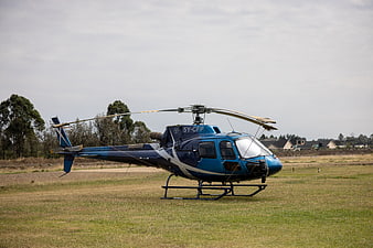 Blue helicopter parked on grassy field with registration 5Y-CFP