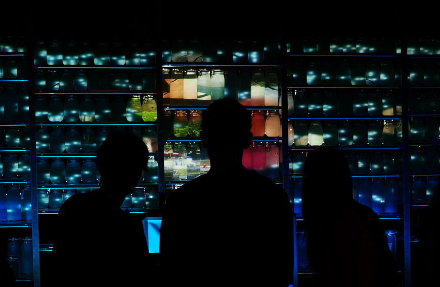 Silhouettes of people in front of colorful glowing jars