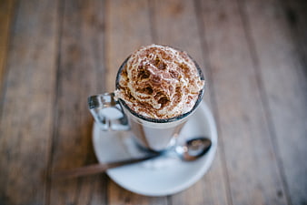 Overhead view of frothy cappuccino with cocoa powder on wooden table