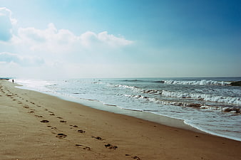 Sandy Beach Shoreline with Footprints and Ocean Waves