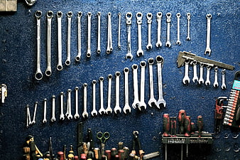Organized wrenches and tools on blue pegboard