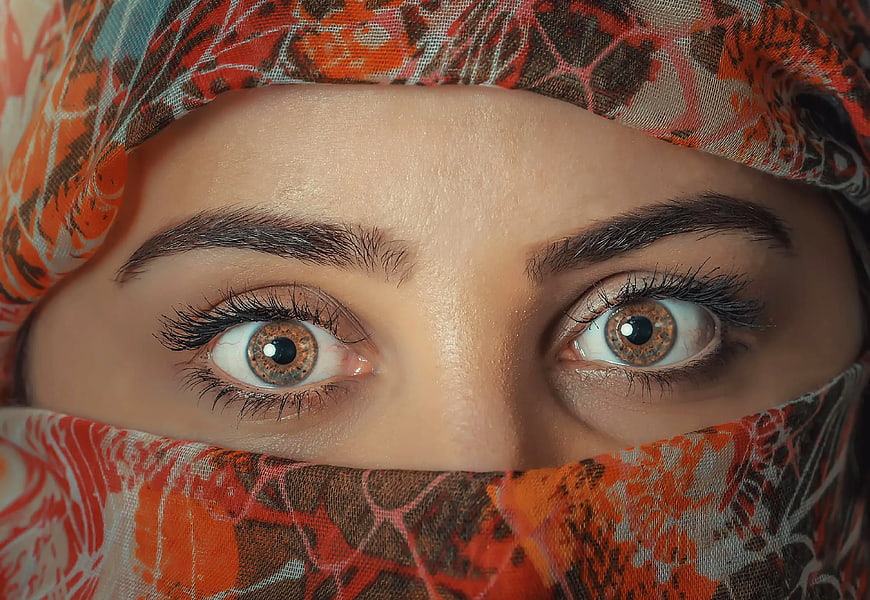 Close-up of woman's eyes wearing patterned orange hijab