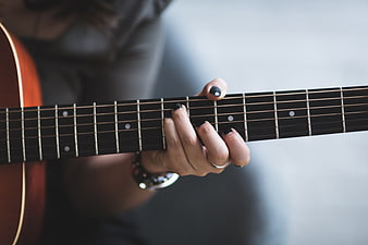 Close-up of woman playing acoustic guitar with black nails