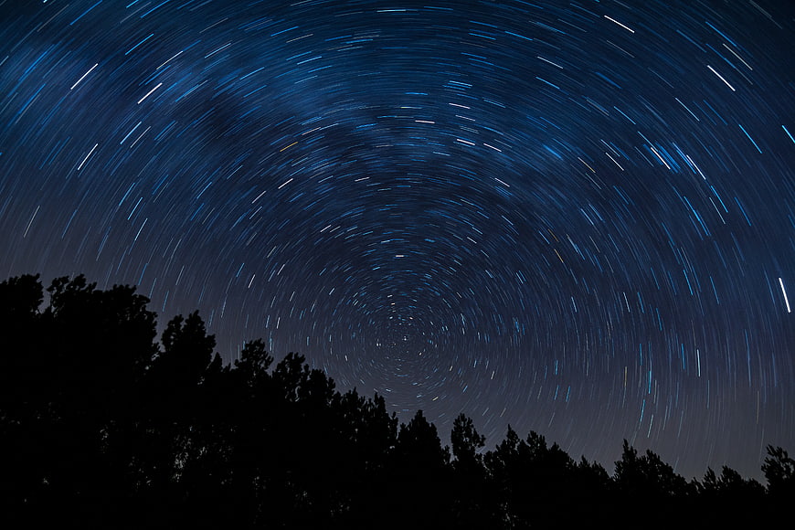 Star Trails Swirling Around Polaris Over Silhouetted Trees
