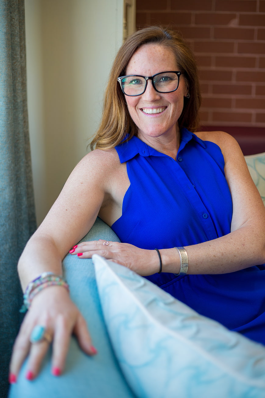 Smiling woman with glasses in blue sleeveless top