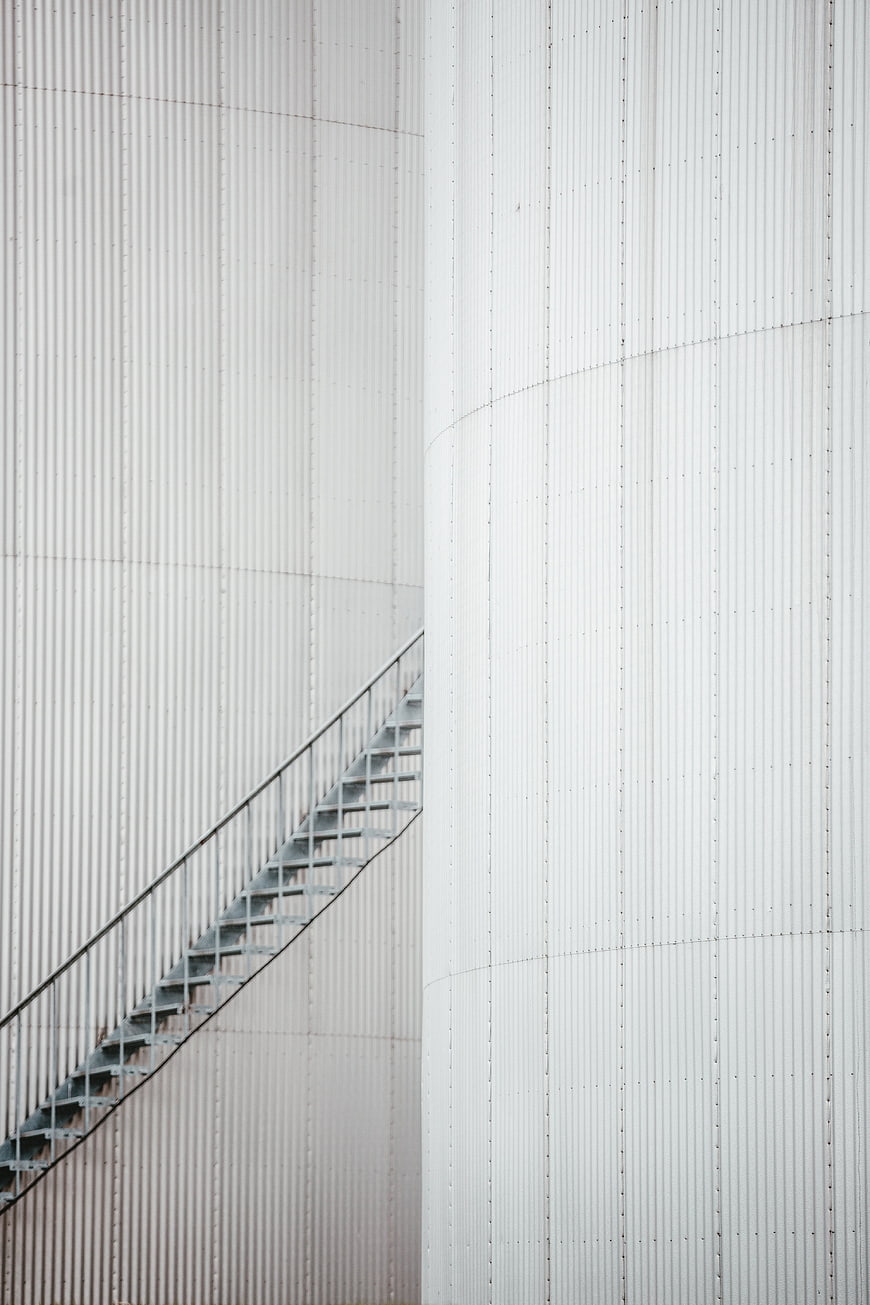 Abstract industrial metal stairs on white corrugated tank wall