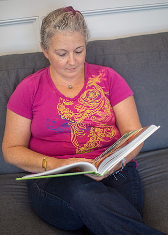 Woman Reading Book on Gray Sofa at Home