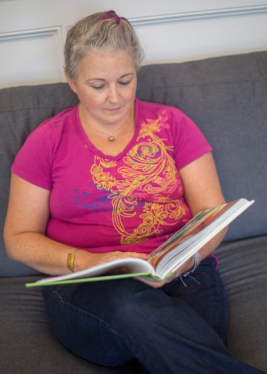 Woman Reading Book on Gray Sofa at Home