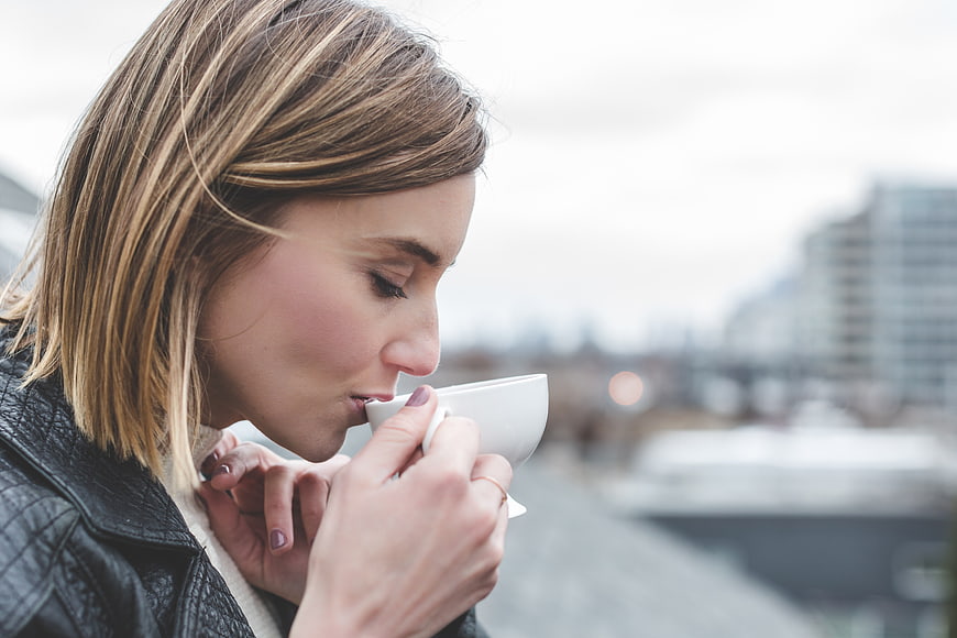 Woman Sipping Hot Coffee on Urban Balcony