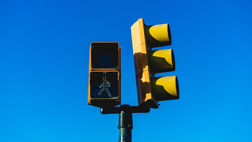 Yellow Traffic Signal and Pedestrian Crossing Light Against Blue Sky