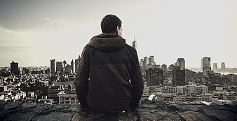 Man sitting on rooftop overlooking city skyline