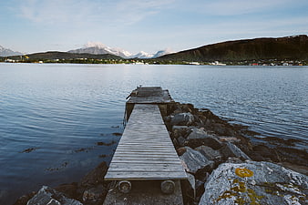 Wooden Dock Extending into Calm Water with Mountains