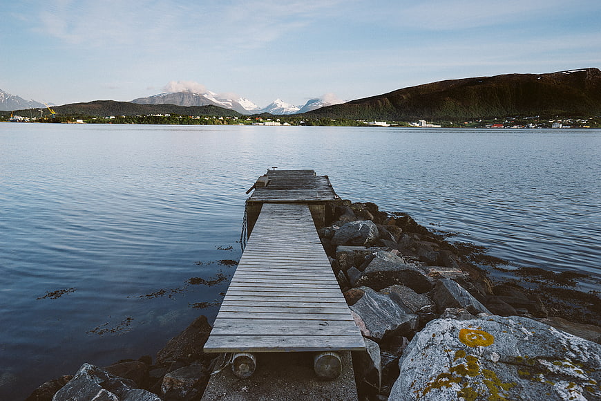 Wooden Dock Extending into Calm Water with Mountains
