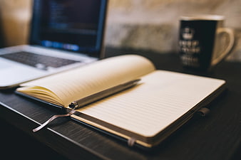 Open Notebook with Pen on Desk Near Laptop and Coffee