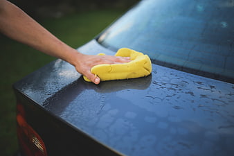 Hand washing car with yellow sponge