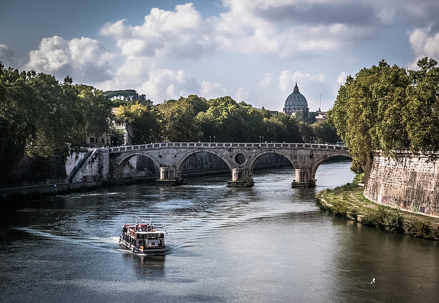 Tourist boat on Tiber River with St. Peter's Basilica in Rome