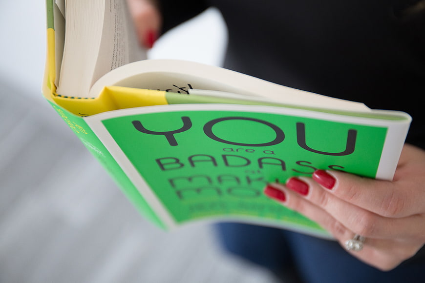 Close-up of woman reading motivational book with red nails
