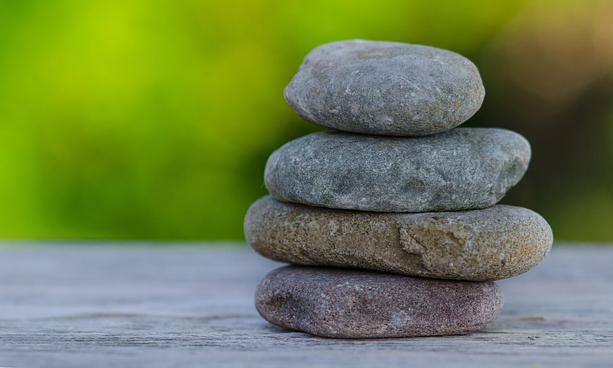 Stacked Zen Stones on Wooden Surface with Green Background