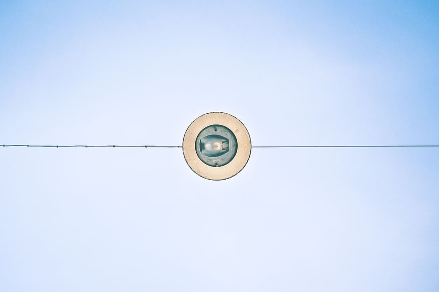 Minimalist street lamp on wire against blue sky