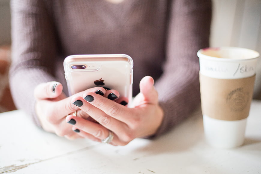 Woman using smartphone with coffee cup on table
