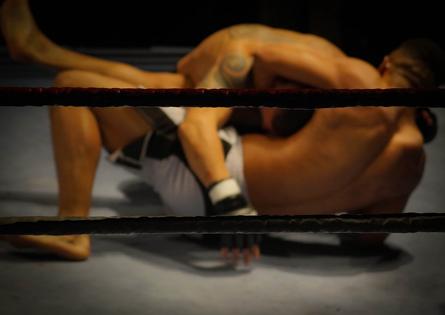 MMA fighters grappling on the ground in a boxing ring