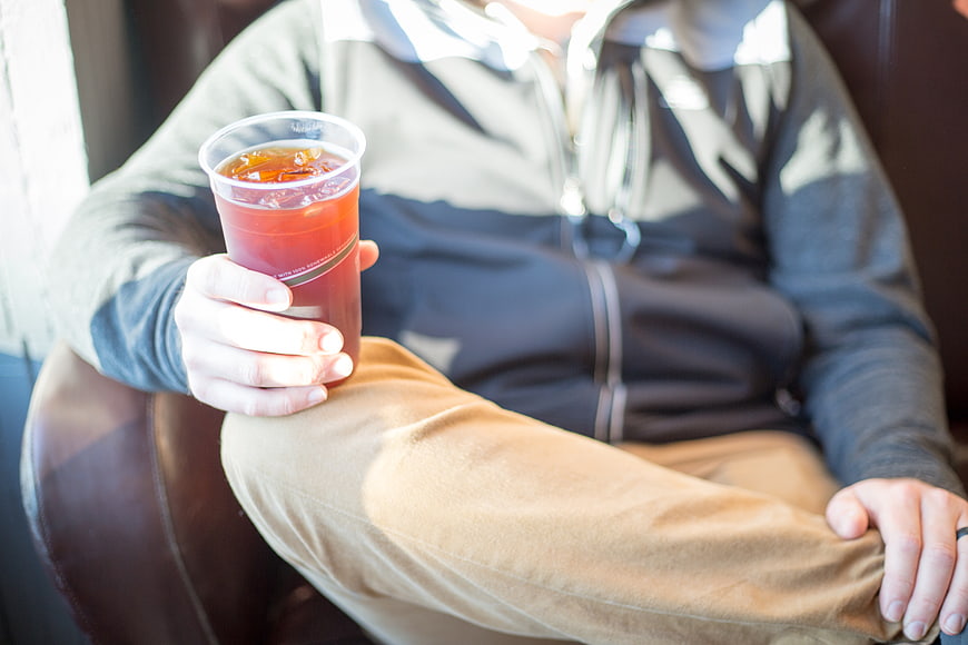Man holding iced coffee in a casual cafe setting