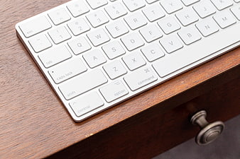 Close-up of white wireless keyboard on wooden desk