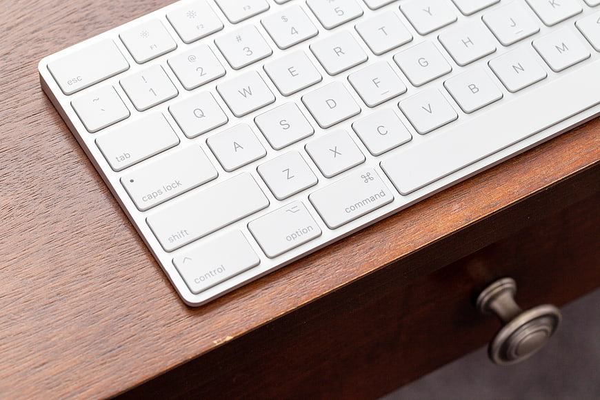 Close-up of white wireless keyboard on wooden desk
