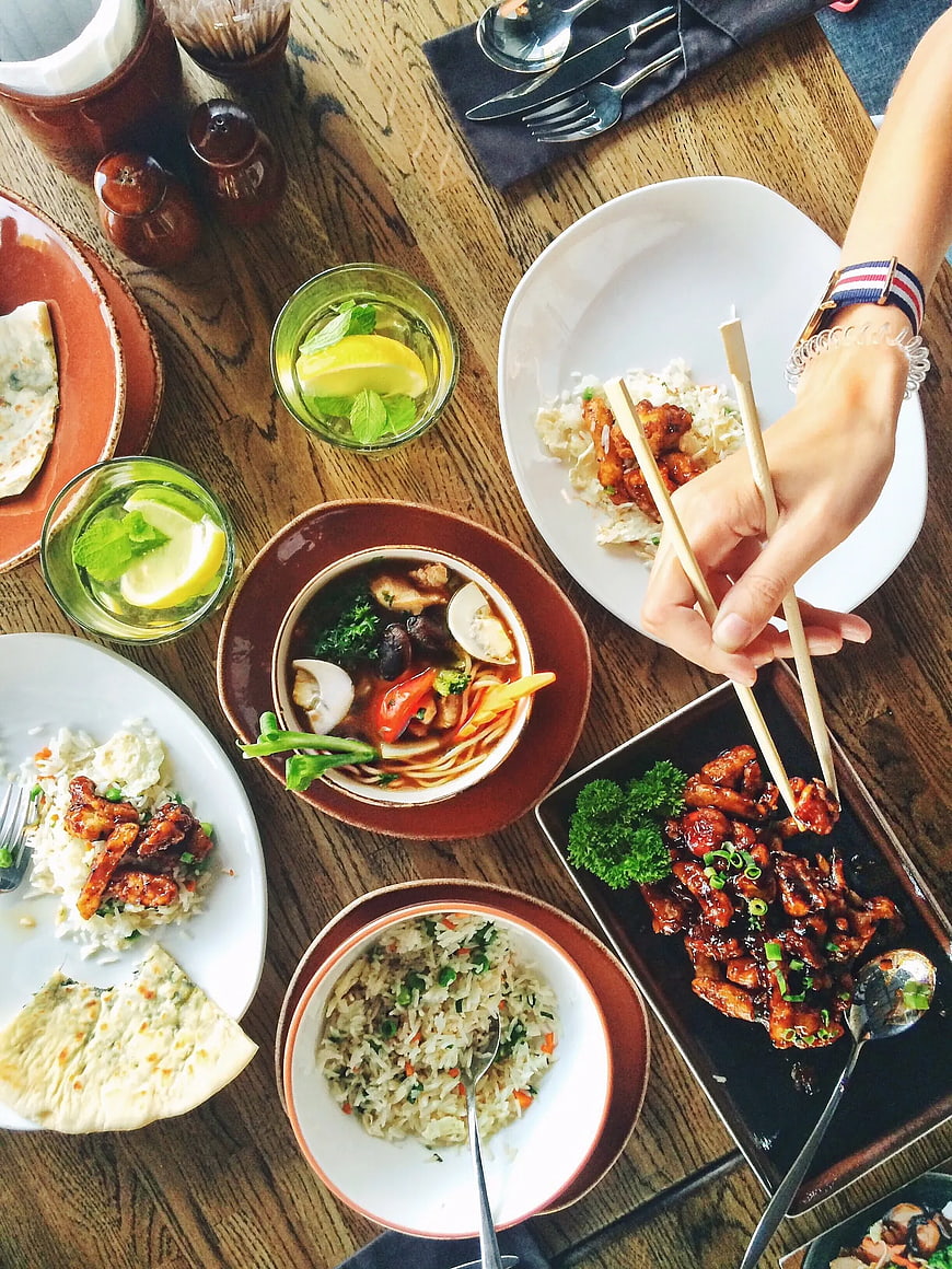 Overhead view of diverse Asian dishes on wooden table