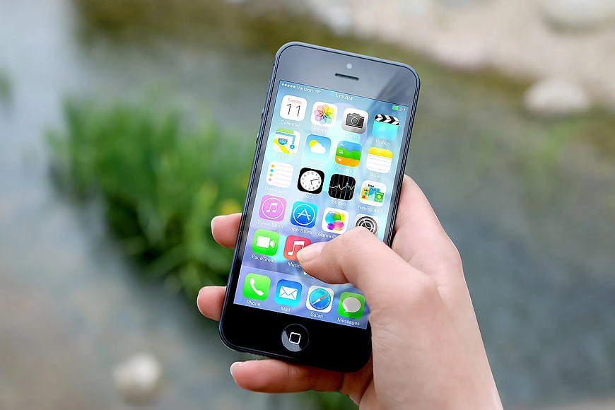Hand holding black iPhone 5 outdoors