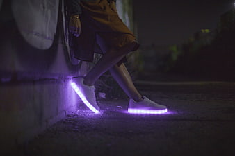 Woman wearing glowing LED sneakers at night