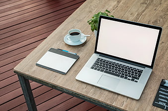 Laptop workspace with coffee and notebook on wooden table